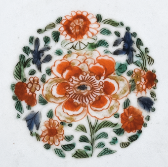 圖為清代五彩花卉紋碟細(xì)節(jié)圖，碟心主題紋飾為團(tuán)花圖，紅花綠葉，相映成趣。（來(lái)源：廣州十三行博物館）